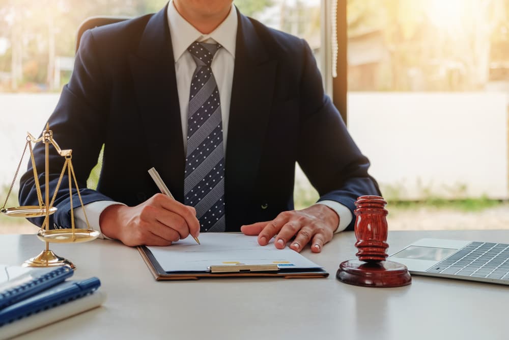 Close-up of a lawyer's desk featuring a gavel, legal documents, and a branded nameplate, symbolizing the legal profession and courtroom advocacy.